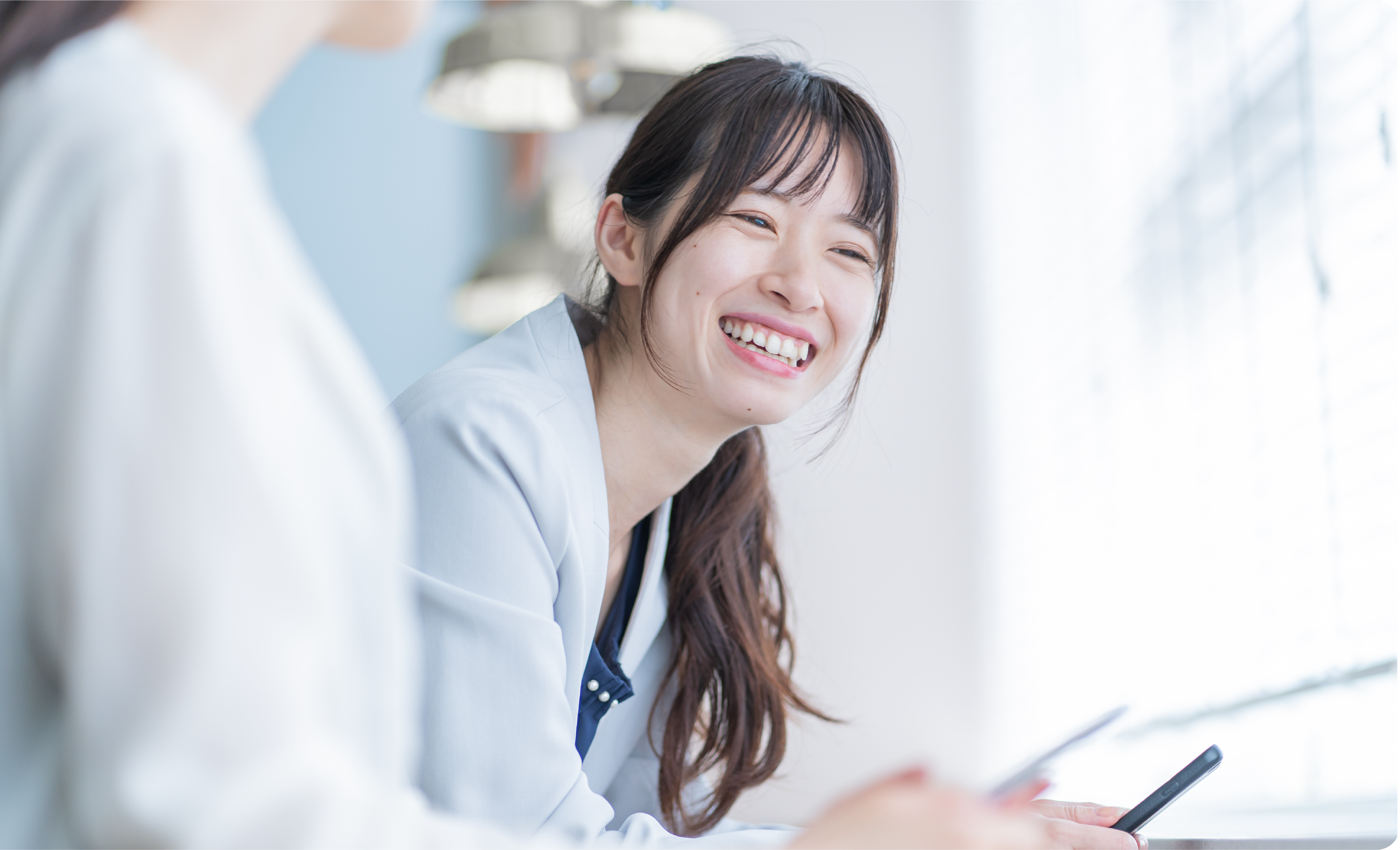 reQruの採用LPテンプレートページ2の社内の仲間と談笑する女性